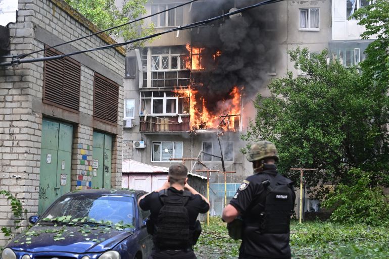 Policemen react in front of a burning building after an air strike hit the courtyard of civilian residences in the centre of Kramatorsk, eastern Ukraine, on July 19, 2022
