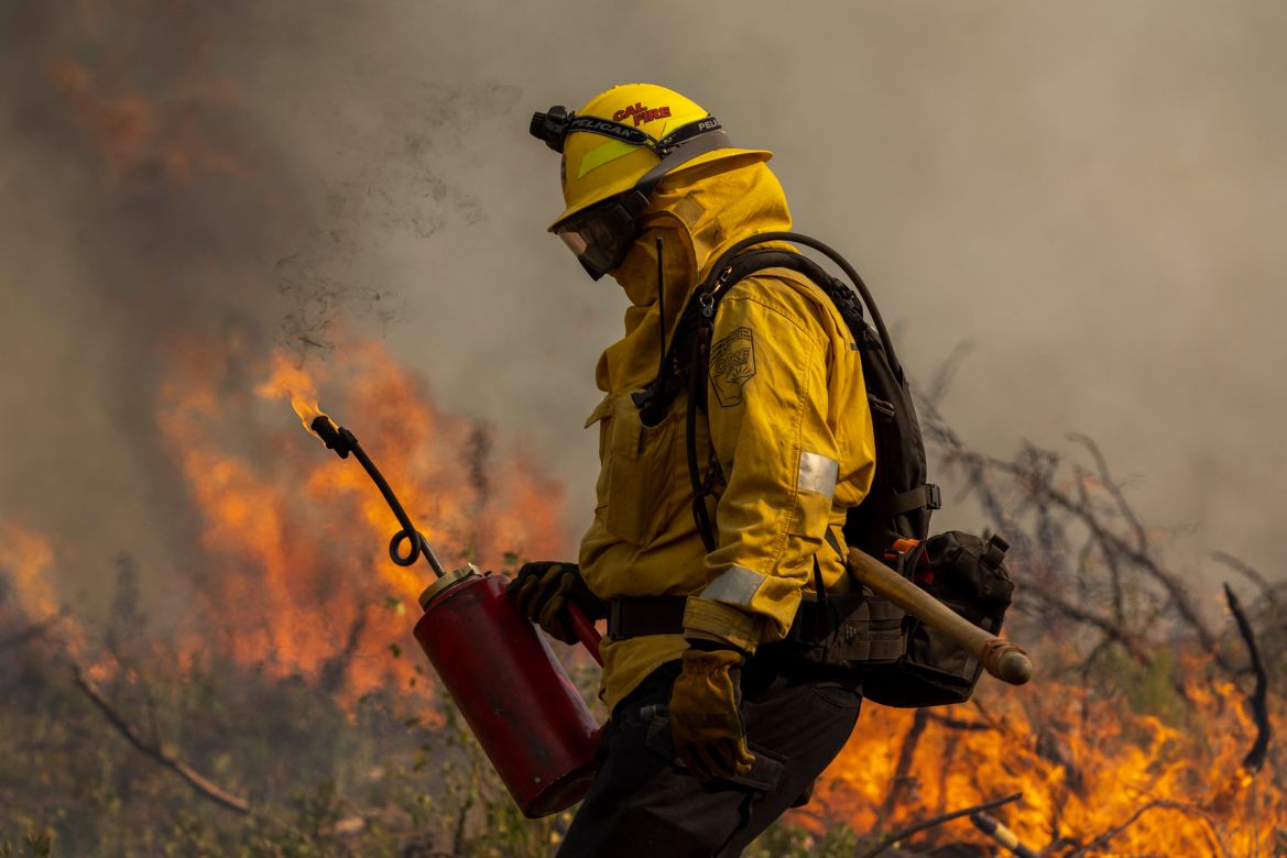 A firefighter uses a drip torch to light a backfire at the Oak Fire near Mariposa