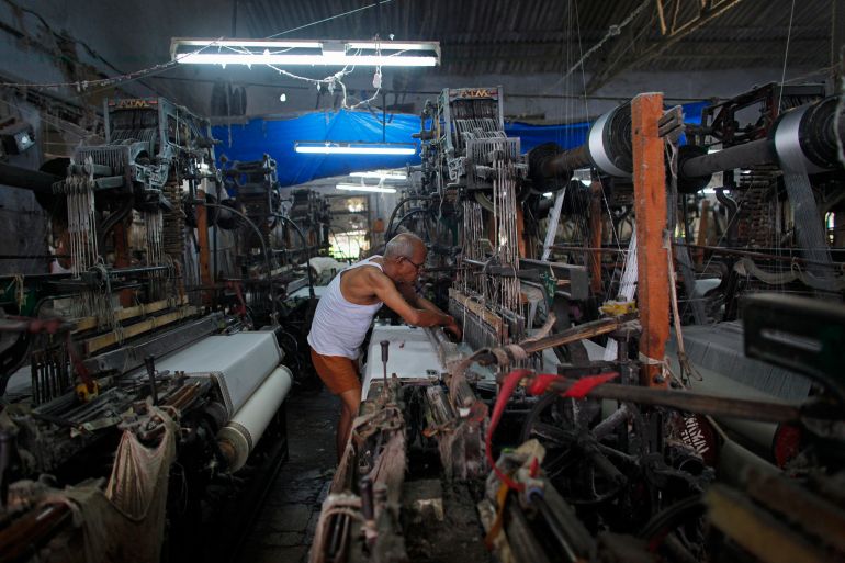 An employee operates a power loom as he weaves saris in Bhiwandi, Maharashtra