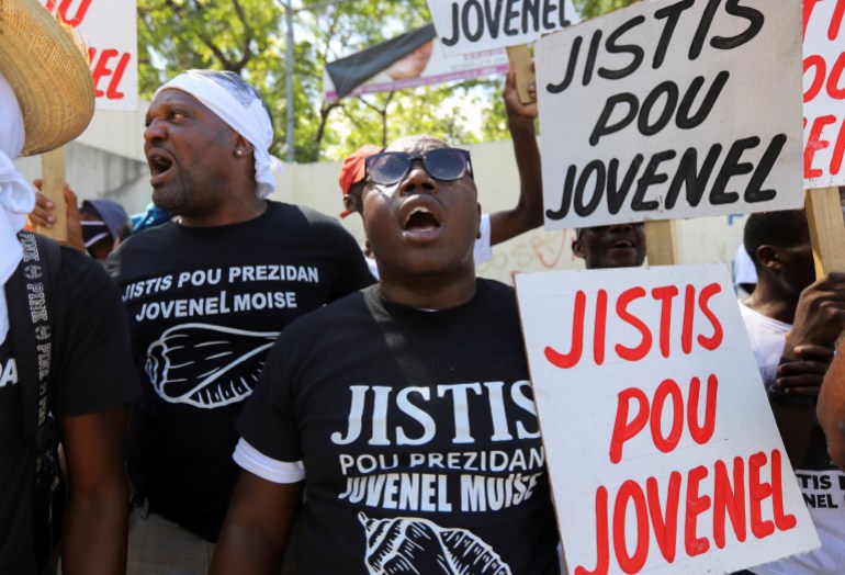 Demonstrators in Haiti hold signs reading, 'Justice for Jovenel'