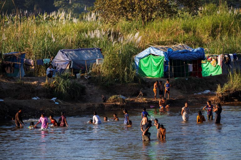 Refugees, who have fled a flare-up in fighting between the Myanmar army and insurgent groups and settled temporarily on the Moei River Bank, bathe in the river waters on the Thai-Myanmar border, in Mae Sot, Thailand, January 7, 2022.