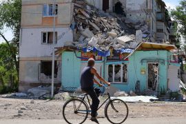 A local resident rides a bicycle past a heavily damaged building in the city of Sievierodonetsk in the Luhansk Region.