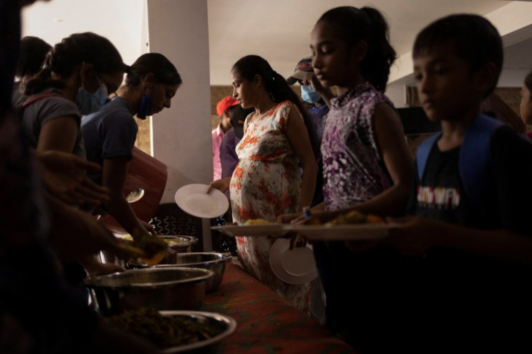 People stand in a queue as they receive food at a community kitchen