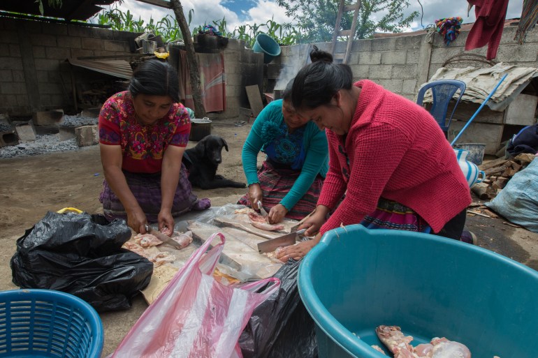 Women prepare chicken for visitors in the family home of Pascual Melvin Guachia in Guatemala