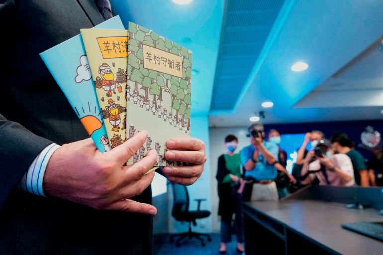 Li Kwai-wah, senior superintendent of Police National Security Department, poses with evidence including three children's books on stories that revolve around a village of sheep which has to deal with wolves from a different village, before a press conference in Hong Kong Thursday, July 22, 2021. Hong Kong's national security police on Thursday arrested five people from a trade union of the General Association of Hong Kong Speech Therapists on suspicion of conspiring to publish and distribute seditious material, in the latest arrests made amid a crackdown on dissent in the city. (AP Photo/Vincent Yu)