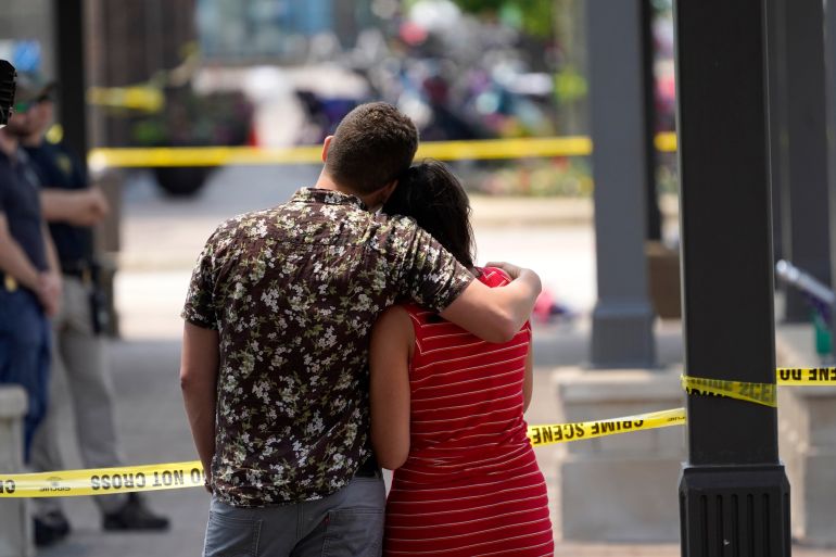 Brooke and Matt Strauss, who were married Sunday, hug while look towards the scene of the mass shooting in downtown Highland Park, Illinois.