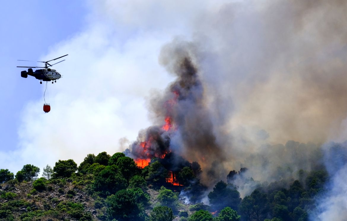 A helicopter launches water as a wildfire advances near a residential area in Alhaurin de la Torre, Malaga, Spain