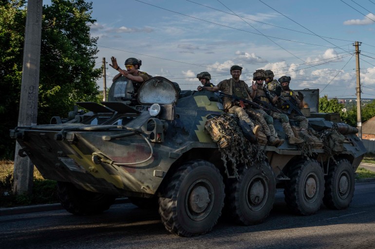 Ukrainian soldiers ride a tank, on a road in Donetsk region