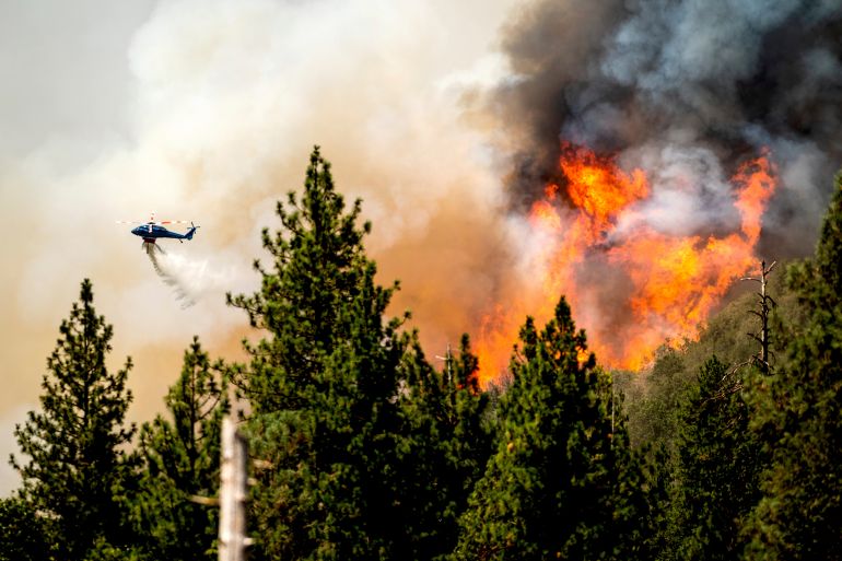 A helicopter drops water on the Oak Fire in California.