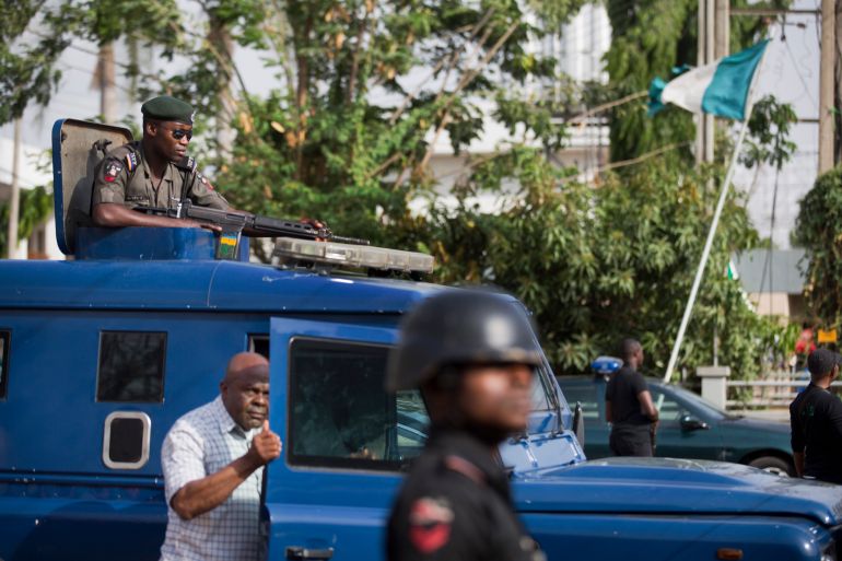 Nigerian police officers and State Security Service agents keep guard as a convoy carrying ballot papers