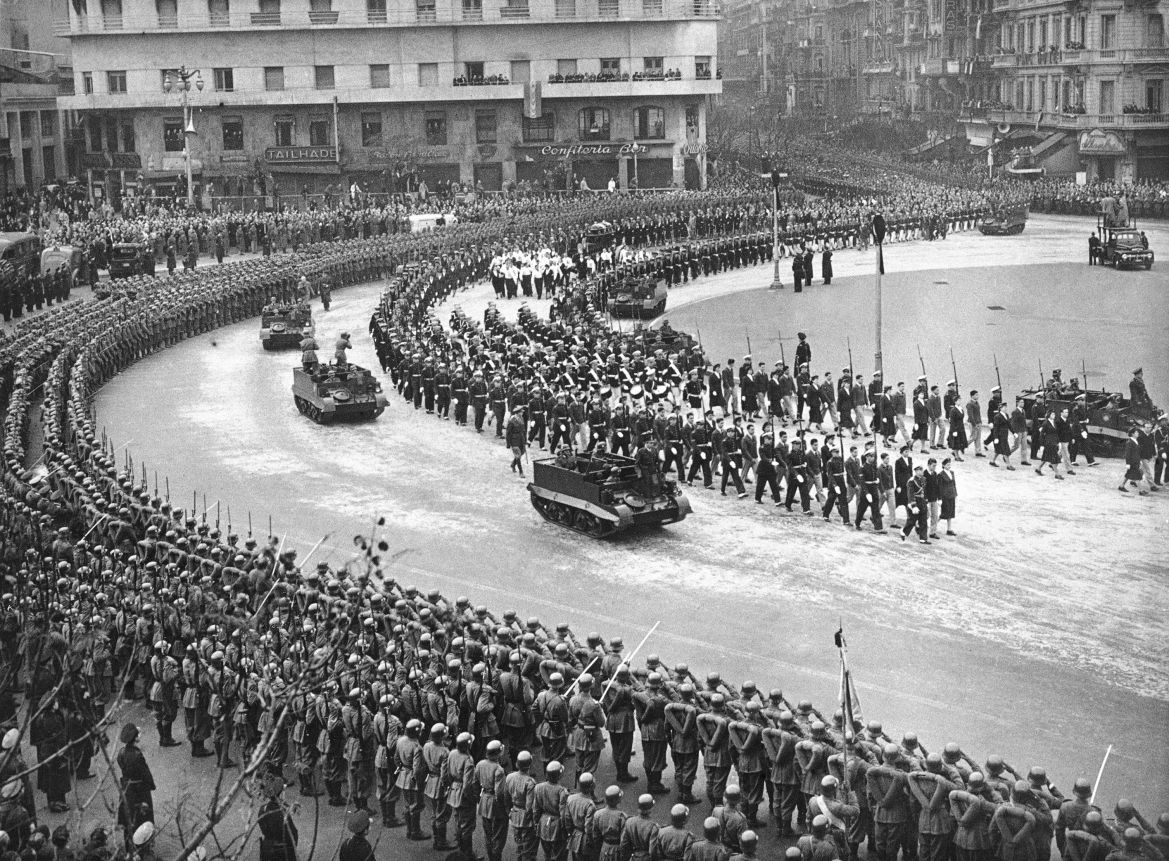 Helmeted soldiers salute as the gun carriage carrying the body of Eva Peron passes them as the funeral cortege made its way to the national capitol in Buenos Aires, Aug. 9, 1952. A double file of cadets and nurses flank the casket which is preceded by a military band playing the funeral march. (AP Photo)