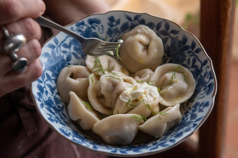 A bowl of meat filled Pelmeni (Dumplings) served with sour cream and dill