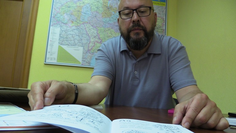 Linguist Oleksandr Rybalko shows a book in a Greek dialect spoken in Ukraine [Mansur Mirovalev/Al Jazeera]