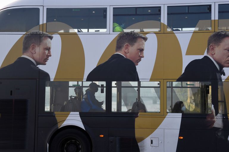 Passengers ride on a bus covered in an advertisement for the new James Bond film