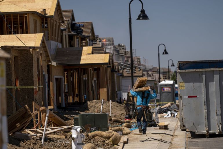 A contractor carries wood boards at a new home construction site in Antioch, California, US