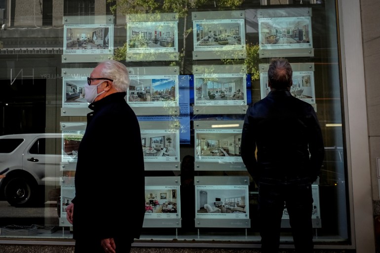 A man looks at advertisements for luxury apartments and homes in the window of a Douglas Elliman Real Estate sales business in Manhattan's upper east side neighborhood in New York City, New York, U.S.