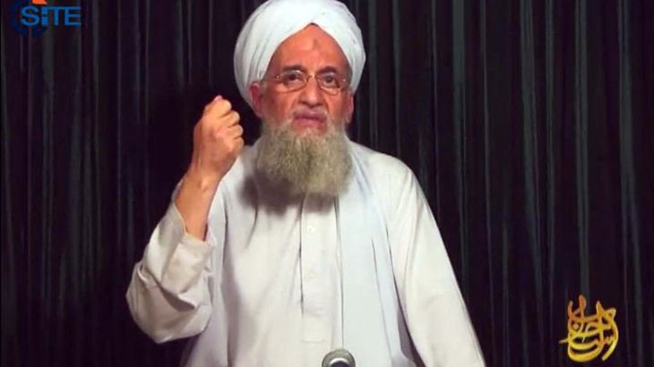 Ayman al-Zawahiri in white clothing and turban gesturing with his hand.