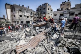 Palestinians inspect the ruins of a collapsed building destroyed by an Israeli air strike in Gaza