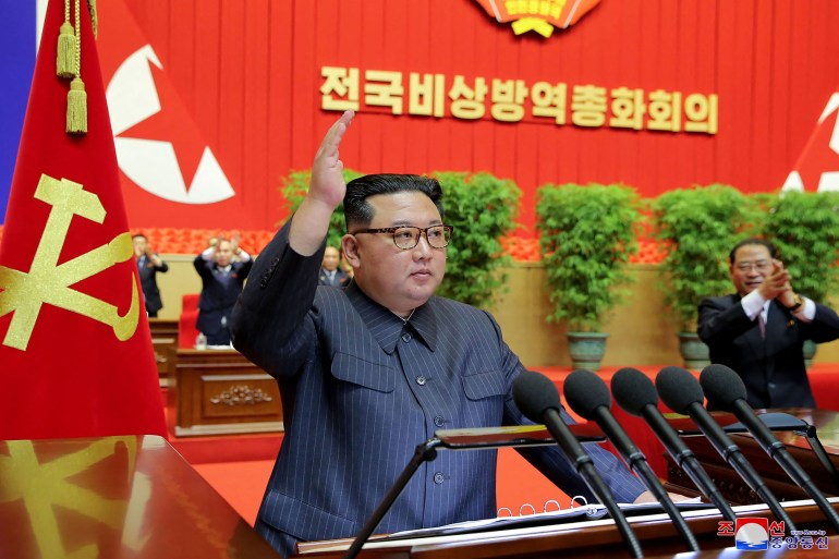 North Korean leader Kim Jong Un speaking at a lectern against a red backdrop to a meeting of health workers and scientists in Pyongyang, North Korea.
