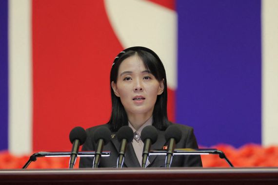 Kim Yo Jong at a conference table in front of a flag.