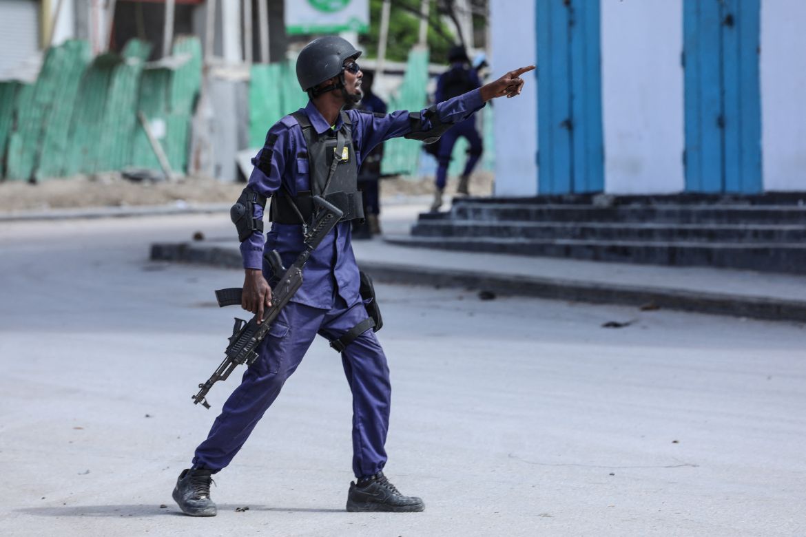 A security officer gestures as he and colleagues patrol at the the site of explosions in Mogadishu, Somalia.