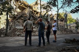 Passers-by stand near a destroyed building following an overnight missile strike in Kharkiv, on August 29, 2022, amid Russia's military invasion launched on Ukraine. (Photo by SERGEY BOBOK / AFP)