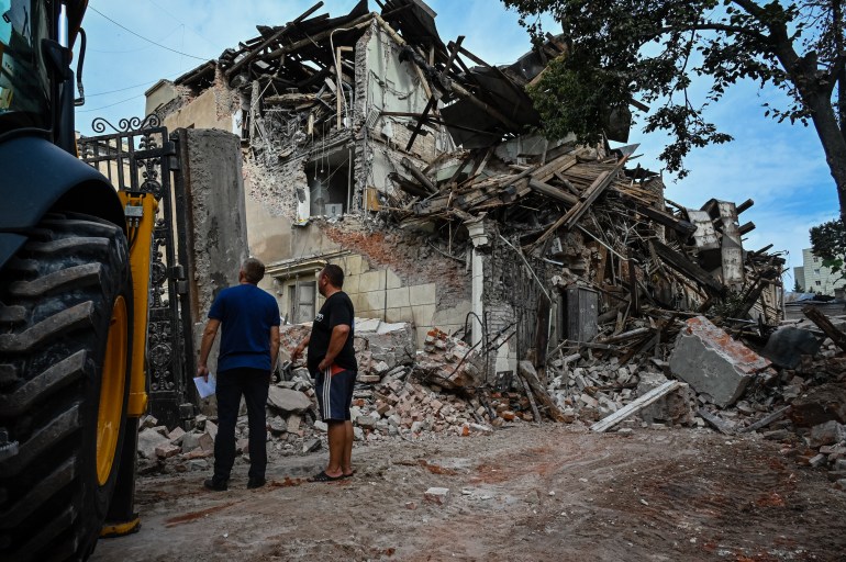 Municipal service workers look at a destroyed building following an overnight missile strike in Kharkiv, on August 29, 2022, amid Russia's military invasion launched on Ukraine. (Photo by SERGEY BOBOK / AFP)