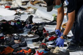 An investigator collects the Lion Air crash victims' belongings at the scene of the accident.