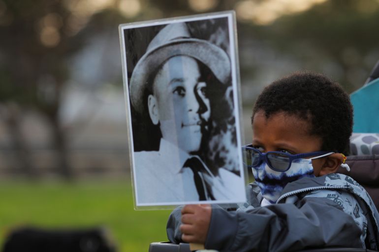 A young boy holds a sign showing the image of Emmett Till