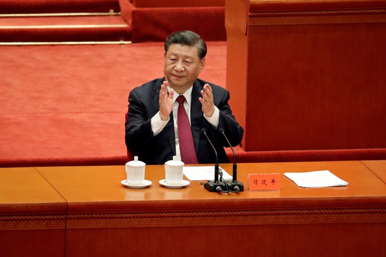 Xi Jinping seated at a desk in the Great Hall of the People clapping