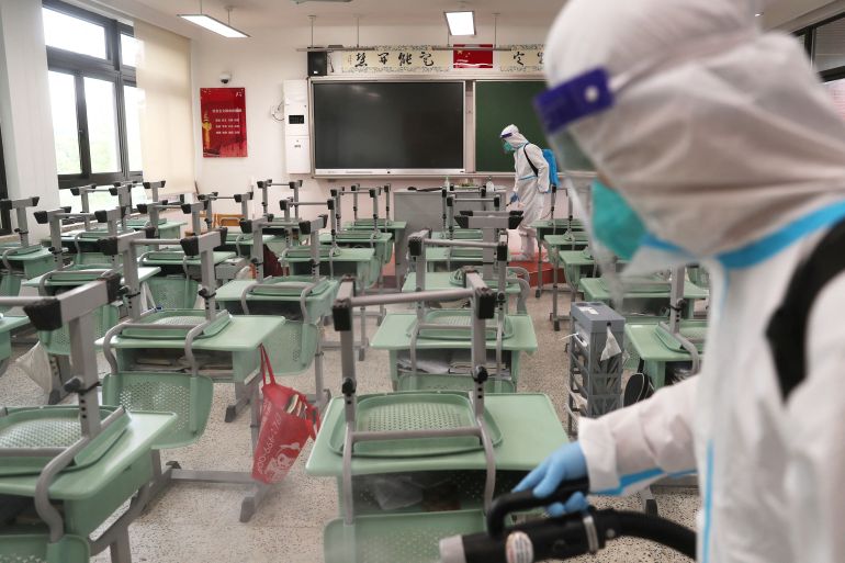 Workers in protective suits disinfect a classroom at a school to prepare for the resumption of classes following the coronavirus disease (COVID-19) outbreak in Shanghai, China.