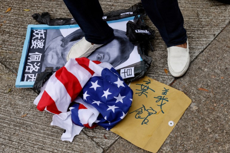 A pro-China supporter steps on a defaced photo of U.S. House of Representatives Speaker Nancy Pelosi during a protest against her visit to Taiwan outside the Consulate General of the United States in Hong Kong, China, August 3, 2022. 