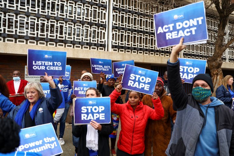 Protesters carry placards, as more than 80 men suspected of gang raping eight women and carrying out an armed robbery of a television crew appear in court in Krugersdorp.