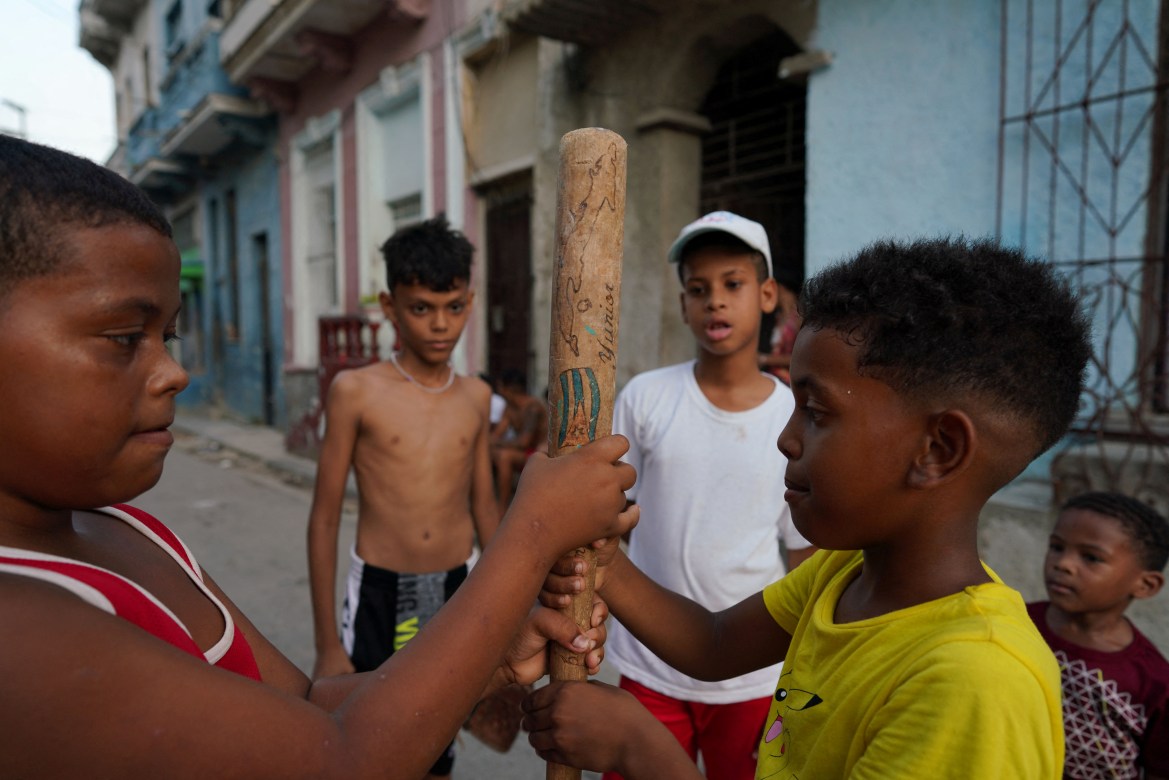 Kevin Kindelan (R), 8, plays baseball with friends in downtown Havana