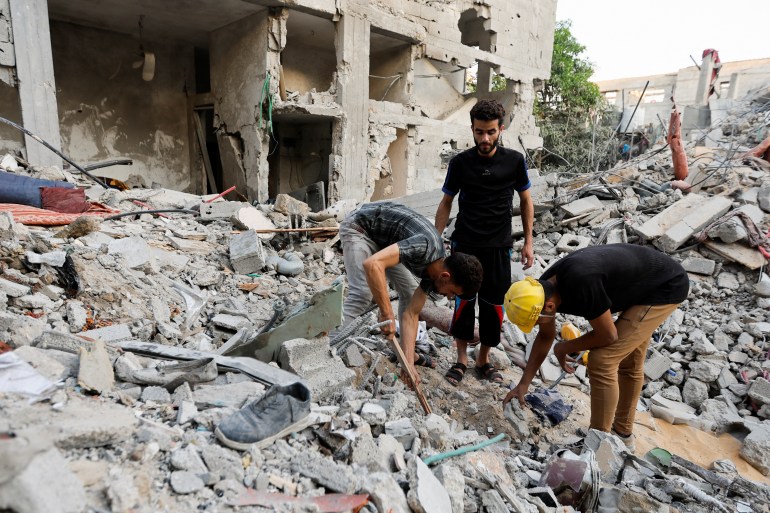 Palestinians men look through debris