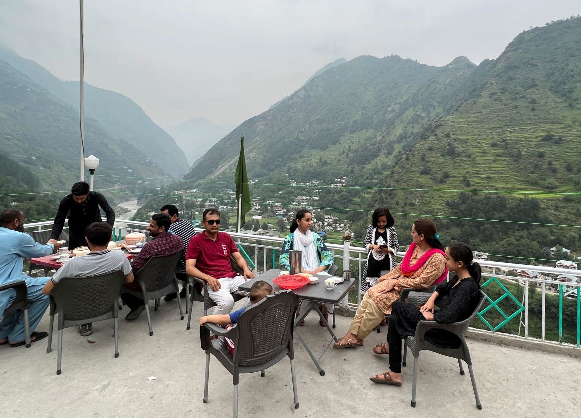 People sit on the roof of a restaurant offering a view of India side