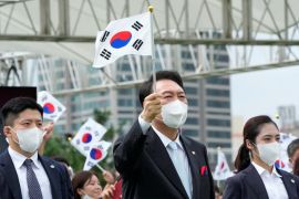 South Korean President Yoon Suk-yeol waves a national flag during a ceremony to celebrate Korean Liberation Day from Japanese colonial rule in 1945, at the presidential office square in Seoul, South Korea, August 15, 2022.