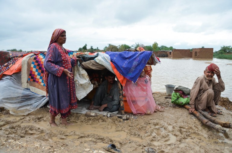 A family takes refuge on a higher ground following rains and floods