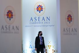 A member of the security team walks in front of the ASEAN hoardings in Phnom Penh
