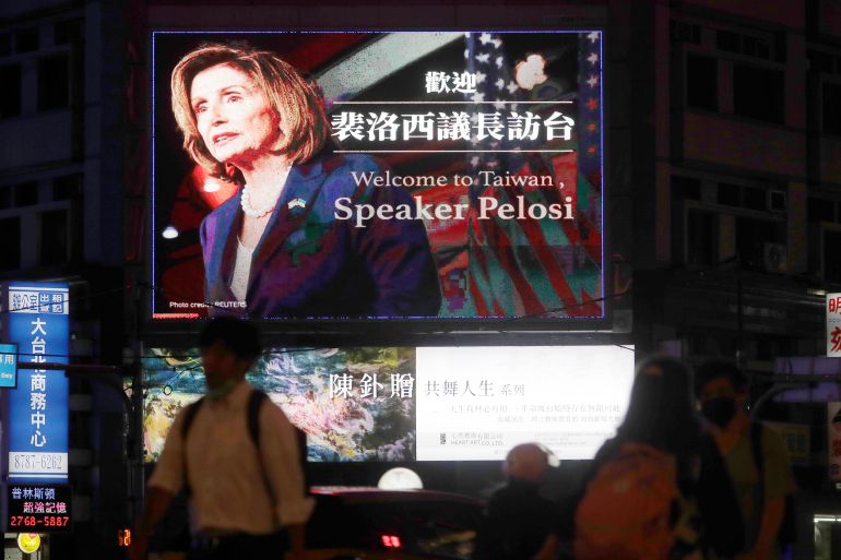 People walk past a billboard welcoming US House Speaker Nancy Pelosi, in Taipei, Taiwan.