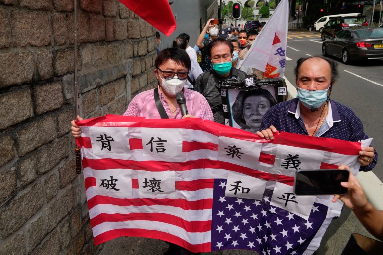 Pro-China supporters hold U.S. flag and a picture of U.S. House Speaker Nancy Pelosi during a protest outside the Consulate General of the United States in Hong Kong, Wednesday, Aug. 3, 2022. 
