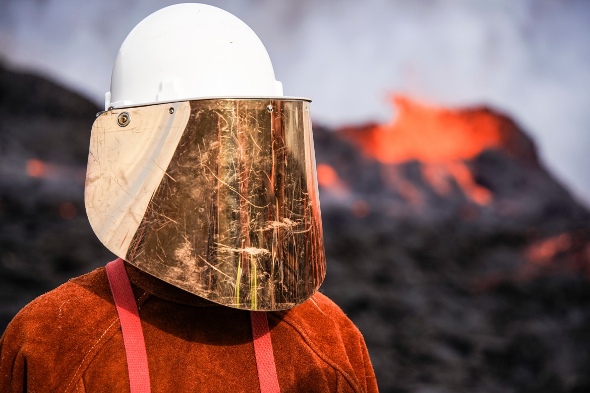 A person wears protective gear as they stand close to the lava