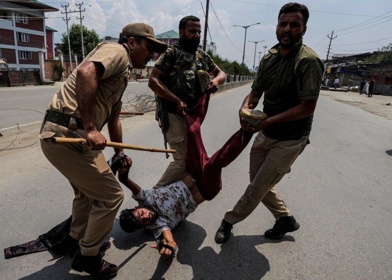 Indian policemen detain a Kashmiri