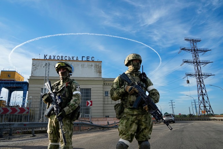 Russian troops guard an entrance of the Kakhovka Hydroelectric Station, a run-of-the-river power plant on the Dnieper River in Kherson region, southern Ukraine