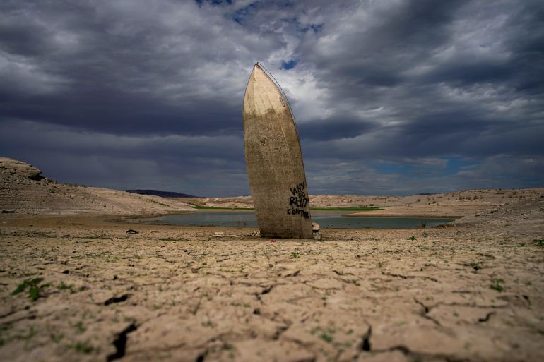 A formerly sunken boat stands upright along shoreline of Lake Mead, US