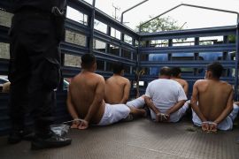 People arrested by police sit in handcuffs in the back of a truck in El Salvador