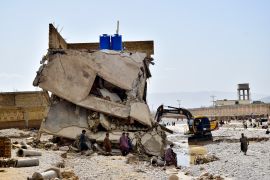 People stand in their partially damage homes caused by flooding after heavy rains, on the outskirts of Quetta.