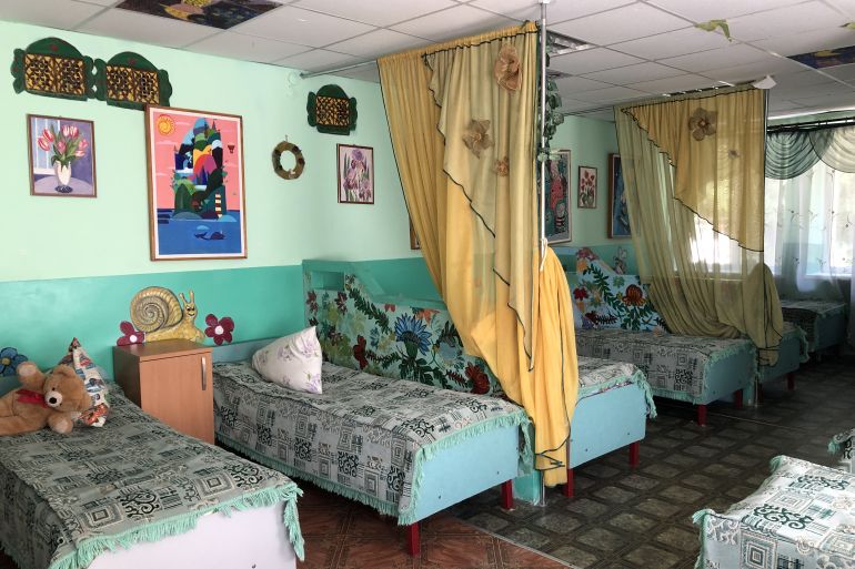 A photo of a bedroom with beds and curtains between every two beds.