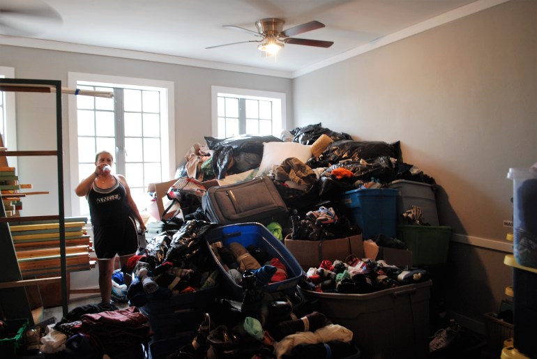 Jessica standing near a large pile of clothes in tubs and suitcases.