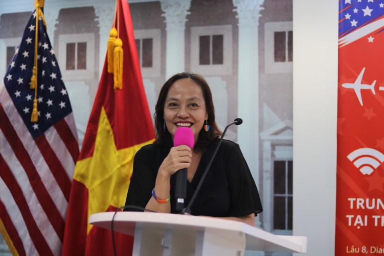 Mong Nguyen speaks at a PFLAG event in front of US and Vietnamese flags